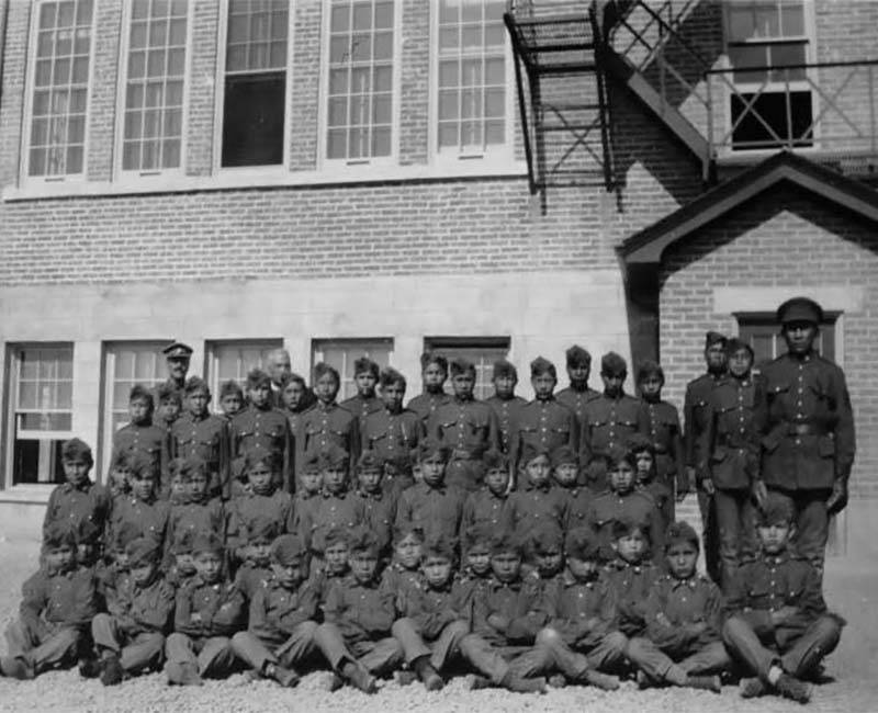 Group of students sitting and standing in front of Cranbrook St. Eugenes School