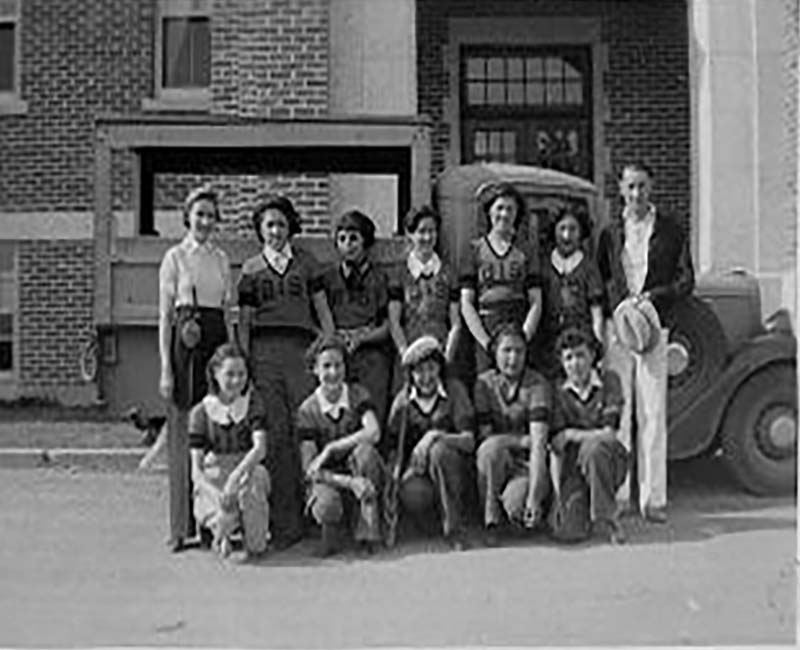 Group of students in front of car in front of Brandon school building