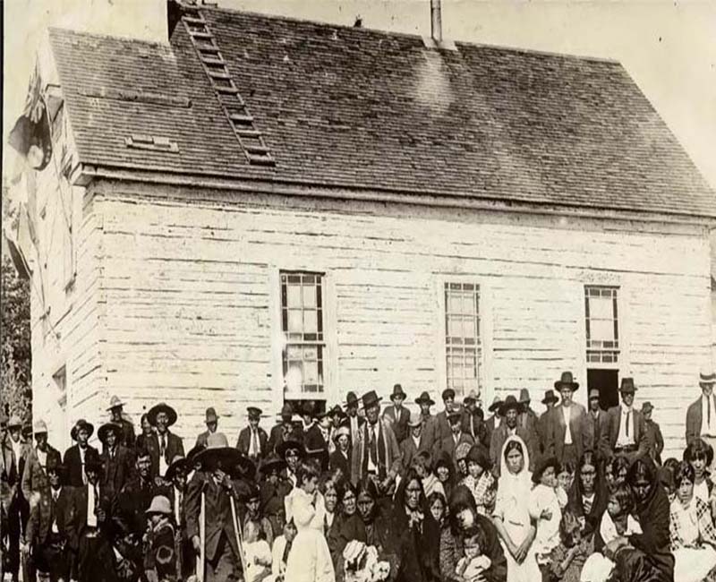 Group of people standing and sitting in front of Cross Lake school building