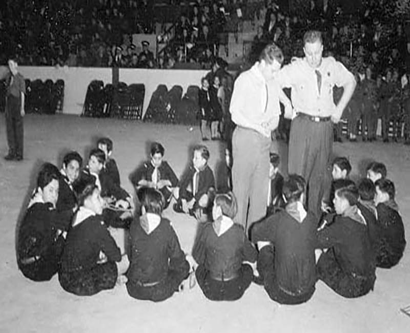Group of children sitting on floor in a circle in Shingwauk school
