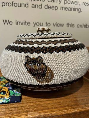 A beaded basket with a wolf face on the front. The basket contains the commingled ashes of sacred fires from all TRC national events.