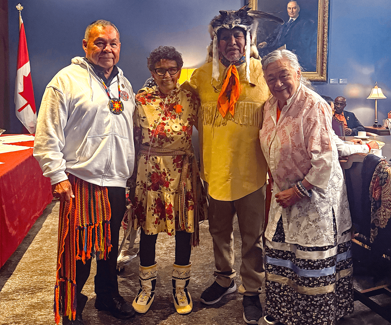 Quatre survivants posent ensemble, souriants, vêtus de tenues traditionnelles issues de leurs cultures respectives